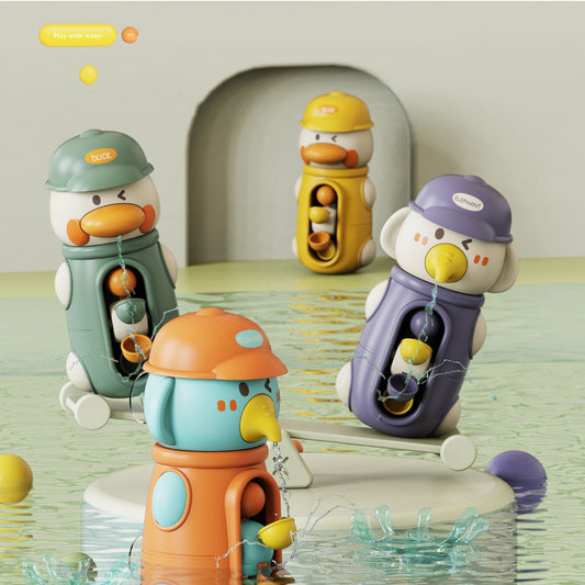Four duck-shaped water fountain toys in different colors (green, yellow, orange, purple) arranged in shallow water with splashes, set against a soft beige background with a small archway.