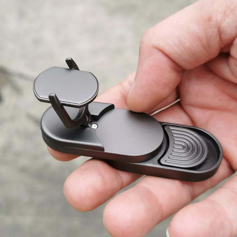 Hand holding a black multi-tool with various components on a blurred background