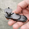 Hand holding a black multi-tool with various components on a blurred background