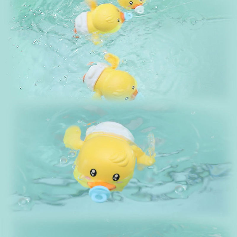 Three yellow duck bath toys wearing white diaper-like bottoms swim in light aqua water, each with a blue pacifier attached.